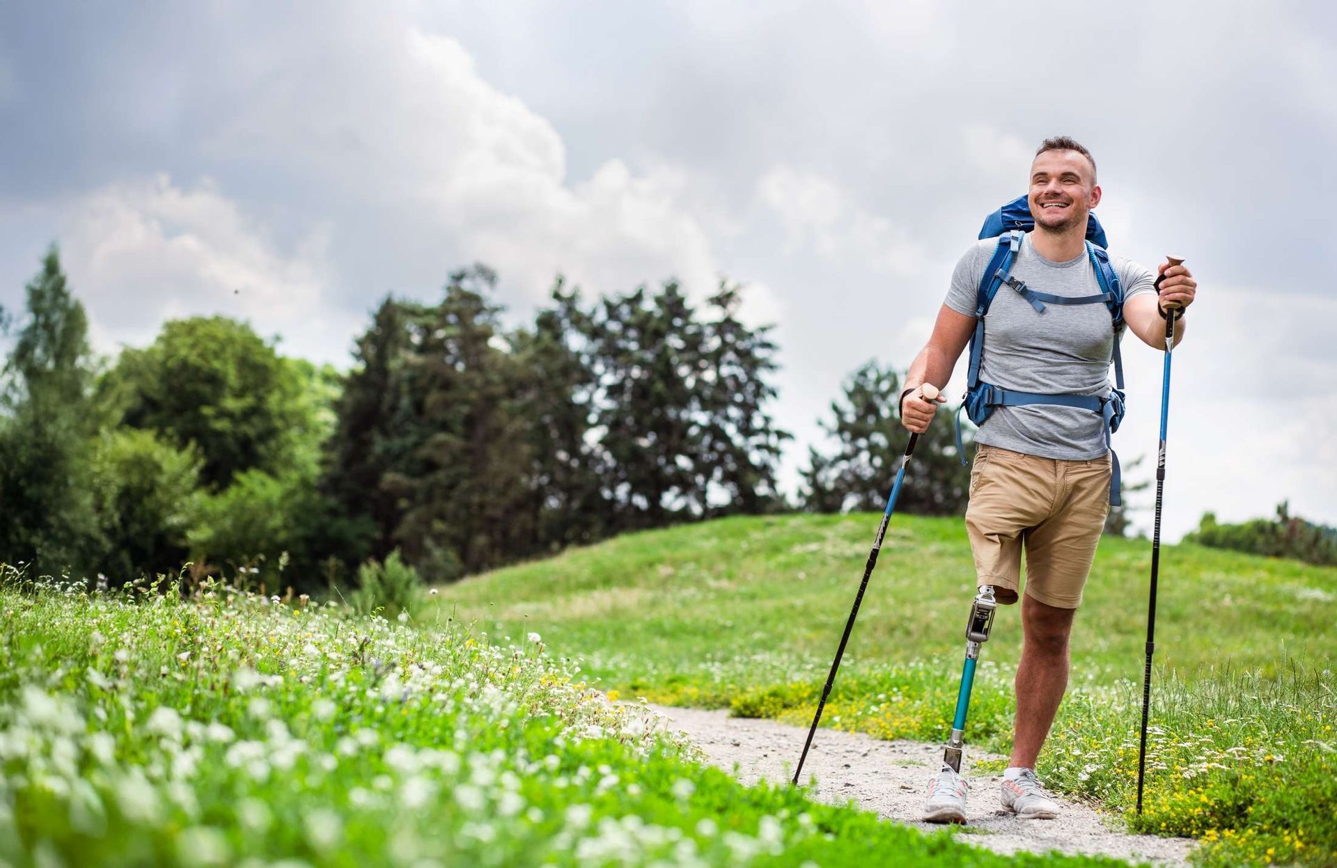 Wanderer läuft auf einem Pfad mit Prothese und Gehhilfe